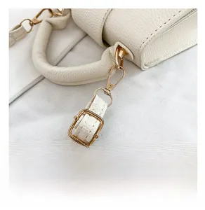 Détails de la boucle métallique dorée sur la bandoulière du sac en cuir blanc