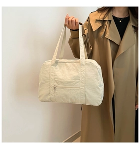 Model showing a large cream nylon tote bag with multiple pockets and shoulder strap