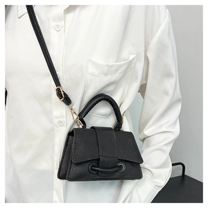 Détail d'un mini sac en cuir noir grainé avec base incurvée distinctive et poignée haute