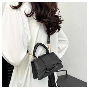 Détail du sac à bandoulière en cuir grainé noir avec poignée et finitions en métal doré