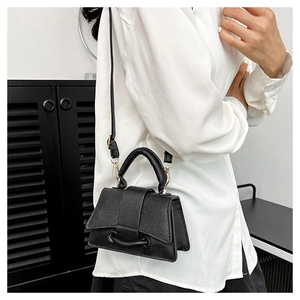 Mini sac bandoulière noir grainé avec boucle dorée porté par un mannequin