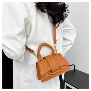 Détail d'un sac bandoulière marron en cuir grainé avec d'élégantes ferrures dorées