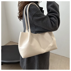 Detail of minimalist cream tote bag with vertical stitching on grey wool coat