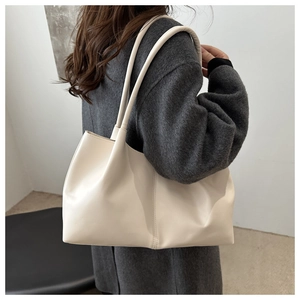Side view of large cream leather tote bag with slim straps worn by a model for commuting