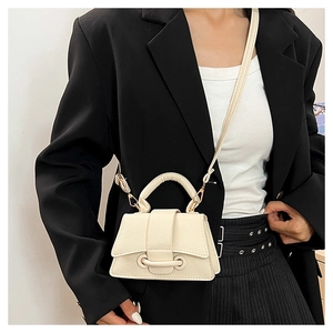 Détail d'un mini sac en cuir crème avec boucle décorative et bandoulière pour un look chic