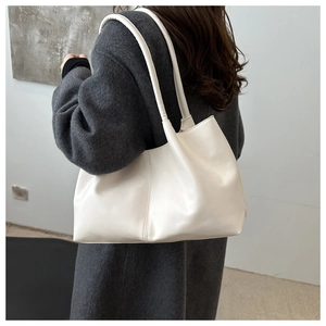 Detailed view of a white large tote bag on a model wearing a grey coat for daily commute