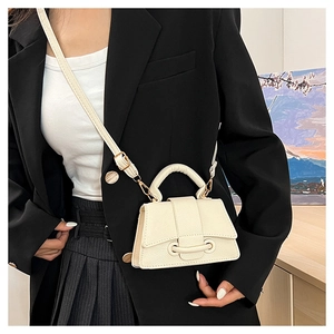 Gros plan d'un mini sac en cuir crème avec détail de boucle porté par un mannequin