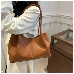 Detailed close-up of a large brown leather tote bag showing soft texture and fine stitching