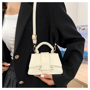 Détail du sac sablier crème en cuir grainé avec sangle décorative et poignée arrondie