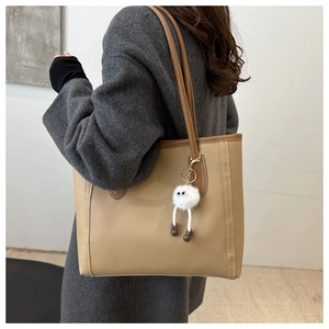 Detail of khaki tote bag with high-quality matte leather and cute plush monster pendant