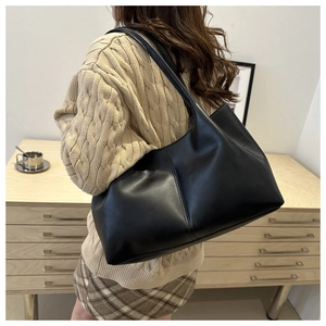 Side view of a large black matte tote bag worn by a model for a commute look