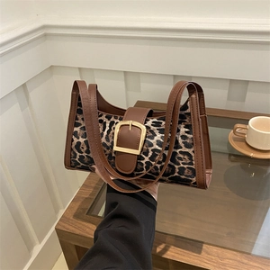 Vintage-Schultertasche mit Leopardenmuster und goldener Schnalle auf einem Holztisch