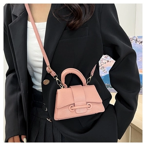 Détail d'un mini sac bandoulière en cuir grainé rose avec une boucle décorative unique