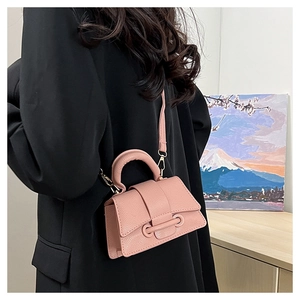 Petit sac à main rose en cuir grainé porté avec un costume noir vue de profil latéral