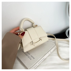 Détail d'un mini sac en cuir crème avec poignée dorée et bandoulière de style élégant