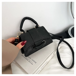 Gros plan du mini sac noir en cuir grainé avec détails argentés et poignée haute