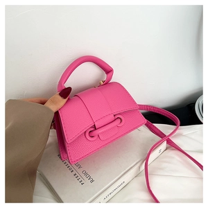Gros plan détaillé du mini sac à main rose vif avec texture galet sur un livre