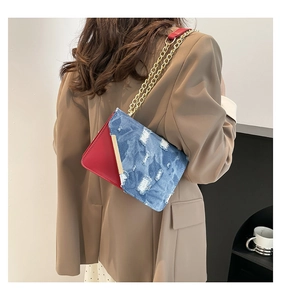 Detail of red leather and distressed denim crossbody bag with gold chain strap