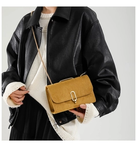 Close-up of vintage yellow suede crossbody bag with gold U-shaped metal buckle and chain