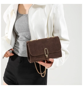 Close-up of retro dark brown suede crossbody bag with elegant golden chain and buckle