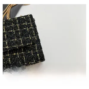 Detail of elegant black and gold tweed fabric with metallic gold chain on a shoulder bag