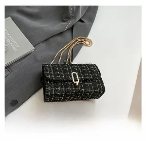 Close-up of black and gold tweed chain bag shown with a smartphone for size reference
