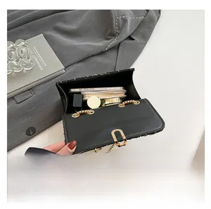 Detailed internal capacity view of black and gold chain bag showing phone and cosmetics