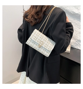 Detail of a chic cream tweed chain bag with gold metal hardware on model side view