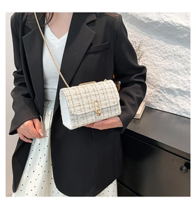Détail du sac à bandoulière en tweed blanc avec chaîne dorée et fermoir métallique