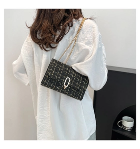 Détail de la texture tweed et chaîne dorée sur un sac bandoulière noir au fini de luxe