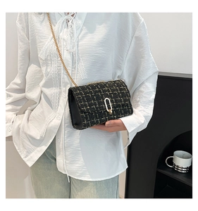 Gros plan du sac bandoulière en tweed noir avec chaîne en métal et fermoir argenté