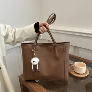 Brown large capacity tote bag with plush charm and adjustable strap for daily commute