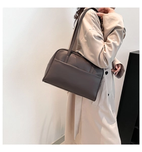 Side view of woman wearing deep brown PU leather underarm bag in minimalist setting