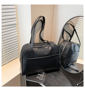 Détail du grand sac cabas noir mat avec deux anses sur une surface en bois clair