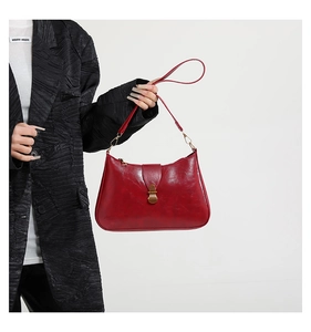 Detail of red glossy leather shoulder bag with vintage gold metal clasp and thin strap