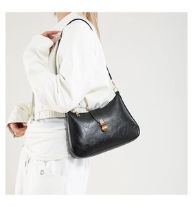 Detail of vintage glossy wrinkled leather shoulder bag with gold clasp on model