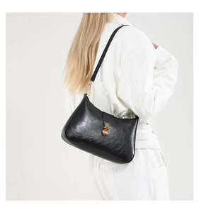 Close-up of black retro underarm bag with gold metal buckle and vintage leather texture