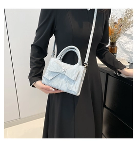 Detail of light blue bow handbag with heart rhinestone on elegant black dress