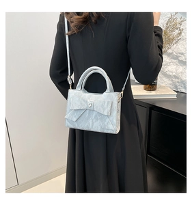 Detailed view of light blue crossbody bag with oversized bow and heart buckle on model