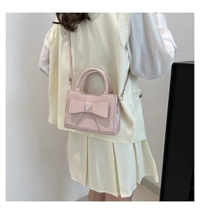 Detailed view of pink crossbody bag with a large bow and silver heart decoration