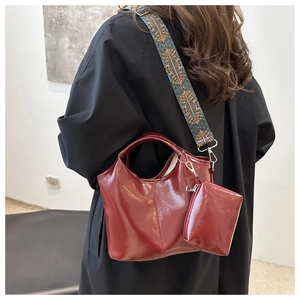 Dettaglio borsa a secchiello bordeaux con tracolla larga a motivi geometrici vintage