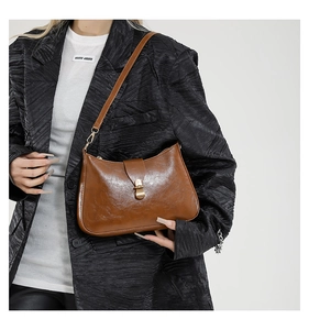 Brown oil-waxed leather hobo bag with vintage metal buckle shown on a model