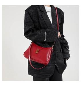 Detail showing vintage red faux leather texture and retro metal buckle on shoulder bag