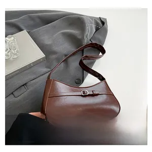 Detail of a dark brown oil-wax leather underarm bag with a silver metal buckle accent