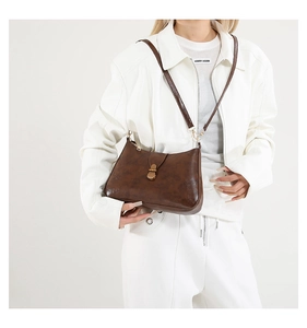 Detail of vintage brown textured leather underarm bag with gold buckle and adjustable strap