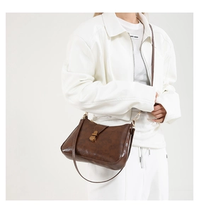 Detail of dark brown vintage faux leather bag with iconic golden twist lock closure