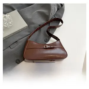 Detail of vintage brown shoulder bag with silver buckle on grey suit background