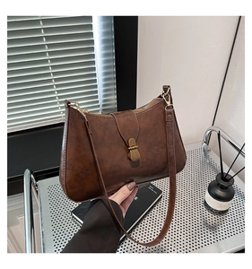 Detailed view of vintage brown leather underarm bag with gold metal buckle and zipper
