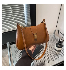 Detailed view of the vintage brown leather handbag with a sleek gold metallic clasp