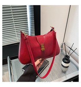 Close-up of deep red leather shoulder bag with vintage gold metal buckle detail